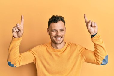 Genç İspanyol adam parmaklarını kaldırıp kameraya bakıyor. Seksi bir ifadeyle, neşeli ve mutlu bir yüzle.. 