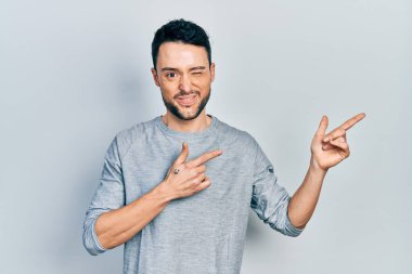 Genç ispanyol adam parmaklarını yana doğru gösteriyor kameraya seksi bir ifadeyle bakıyor, neşeli ve mutlu bir yüzle.. 