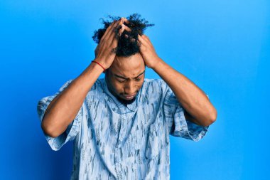 Sakallı, gündelik giysiler giyen, baş ağrısı çeken, çaresiz ve stresli genç Afrikalı Amerikalı bir adam. Ağrı ve migren yüzünden. Eller başının üstünde.. 