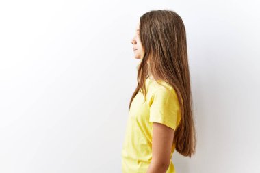 Genç esmer kız, izole edilmiş arka planda yan yana durur, rahat bir görünüm takınır ve kendine güvenen bir gülümseme takınır.. 