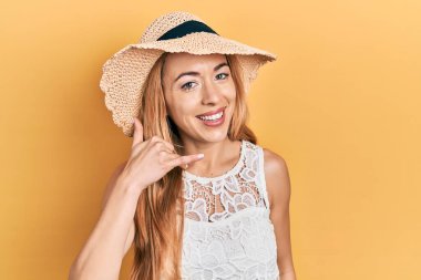 Yazlık şapkalı, gülümseyen, el ve parmaklarıyla telefonla konuşan beyaz bir kadın. iletişim kavramları. 