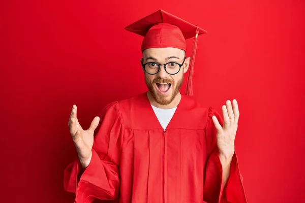 Jovem Ruivo Vestindo Chapéu Formatura Vermelho Roupão Cerimônia Comemorando Surpreso — Fotografia de Stock