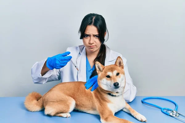 美丽的他的惊慌失措的兽医女士给小狗注射疫苗时 怀疑和紧张 皱着眉头因问题而烦恼 消极的人 — 图库照片