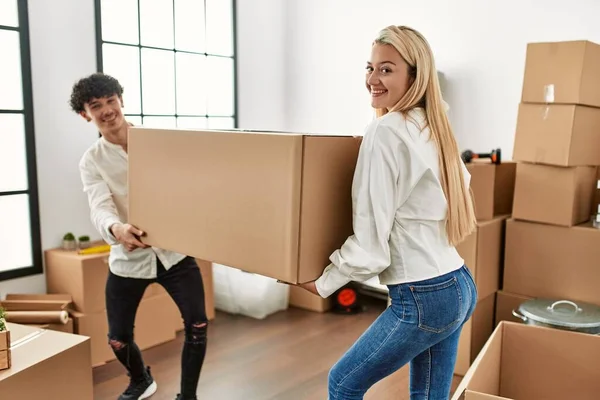 若い美しいカップル笑顔幸せな保持大きな段ボール箱で新しい家 — ストック写真