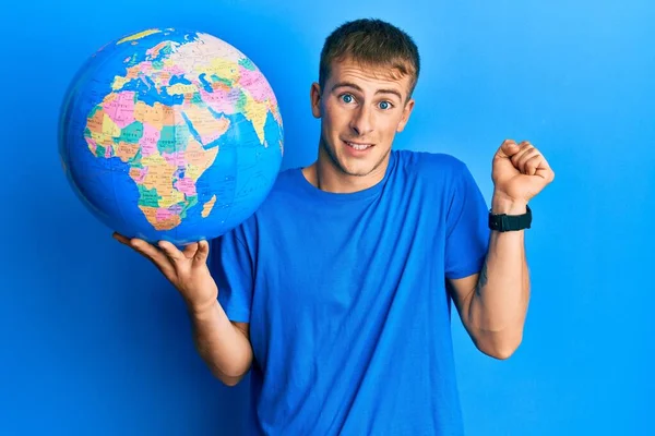 Young Caucasian Man Holding World Ball Screaming Proud Celebrating Victory — Stock Photo, Image
