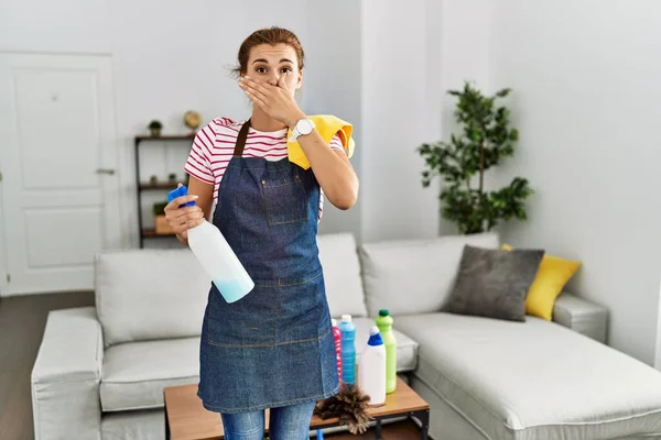 Jonge Brunette Vrouw Draagt Schort Met Schoonmaakmiddelen Thuis Geschokt Bedekken — Stockfoto