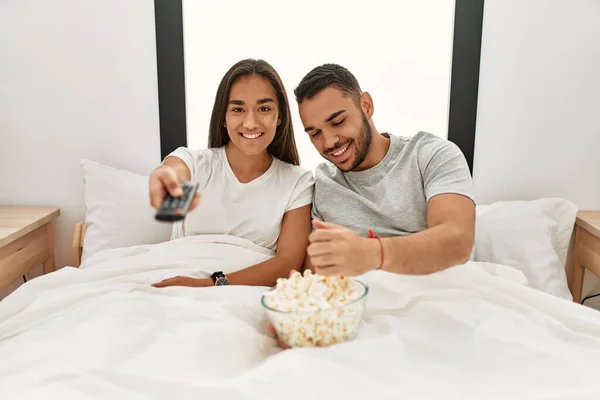 Unga Latinska Par Tittar Film Och Äter Popcorn Liggande Sängen — Stockfoto