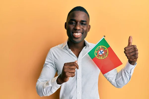 Joven Hombre Afroamericano Sosteniendo Bandera Portugal Sonriendo Feliz Positivo Pulgar —  Fotos de Stock