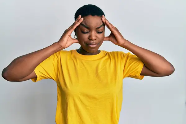 ストレスのため 若いアフリカ系アメリカ人女性の頭の上に手でカジュアルな黄色のTシャツを着て 片頭痛 — ストック写真