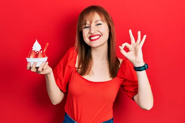 Pelirroja Mujer Joven Sosteniendo Helado Haciendo Signo Con Los Dedos —  Fotos de Stock