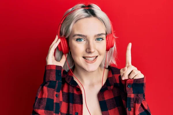 Молода Блондинка Слухає Музику Допомогою Навушників Посміхаючись Ідеєю Або Питанням — стокове фото