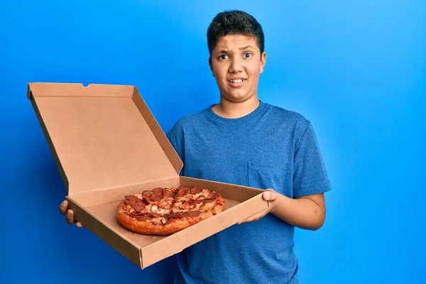 Adolescente Hispano Comiendo Sabrosa Pizza Pepperoni Expresión Despistada Confusa Concepto —  Fotos de Stock