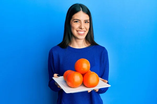 Mujer Hispana Joven Sosteniendo Plato Con Naranjas Frescas Sonriendo Con —  Fotos de Stock