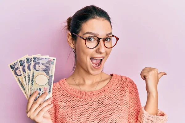 Young Caucasian Woman Holding Japanese Yen Banknotes Pointing Thumb Side — Stock Photo, Image