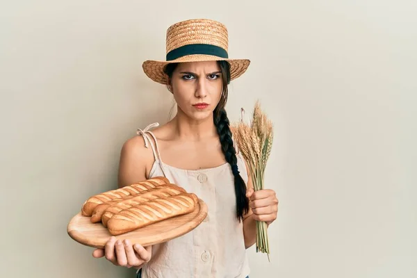 若いヒスパニック系の女性が自家製パンを保持し 問題のために動揺を眉をひそめて小麦懐疑的かつ神経スパイク 否定的な人 — ストック写真