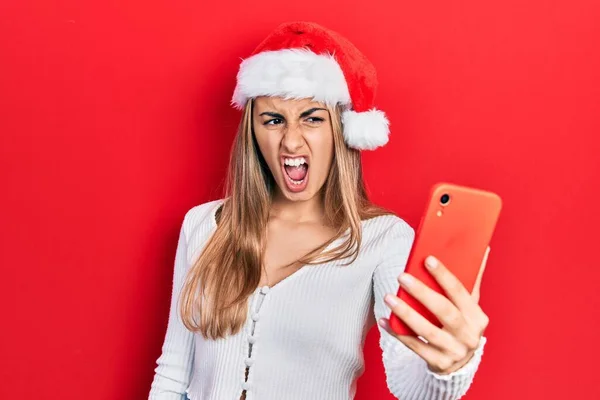 Όμορφη Ισπανίδα Γυναίκα Φορώντας Χριστουγεννιάτικο Καπέλο Χρησιμοποιώντας Smartphone Θυμωμένος Και — Φωτογραφία Αρχείου