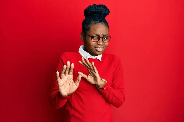 Young african american woman wearing casual clothes and glasses disgusted expression, displeased and fearful doing disgust face because aversion reaction. with hands raised
