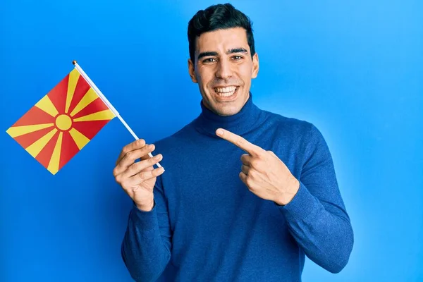Hombre Hispano Guapo Sosteniendo Bandera Macedonia Sonriendo Feliz Señalando Con —  Fotos de Stock