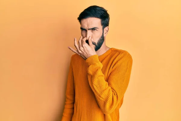 若いヒスパニック系の男性は 鼻の上に指で息を保持し 何か臭いと嫌な 耐え難い匂いを嗅ぐカジュアルな服を着て 臭いが悪い — ストック写真