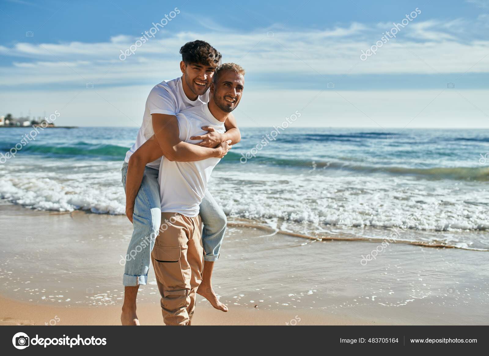 Lovely gay couple on piggyback ride at the beach. Stock Photo