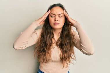 Elleri başının üstünde, günlük kıyafetler giyen genç İspanyol kız, stresten baş ağrısı çekiyor. migren ağrısı. 