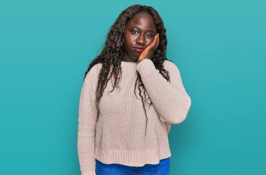 Kışın yün kazak giyen Afrikalı genç bir kadın kollarını kavuşturup depresyondan sıkılmış ve yorgun göründüğünü düşünüyor.. 