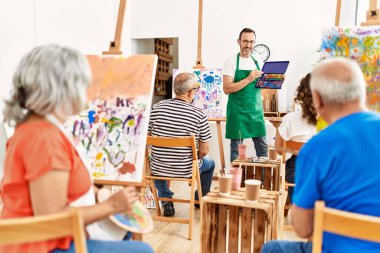 Bir grup orta yaşlı öğrenci resim stüdyosunda resim dersi alıyor..