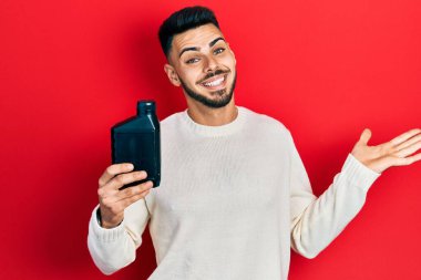 Motor yağı şişesi tutan sakallı genç İspanyol adam başarıyı mutlu bir gülümsemeyle ve kazanan yüz ifadesiyle kutluyor. 