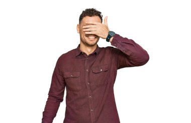 Gündelik kıyafetler giyen, gülümseyen ve gülümseyen genç İspanyol adam şaşırmak için gözlerini kapatıyor. kör kavram. 