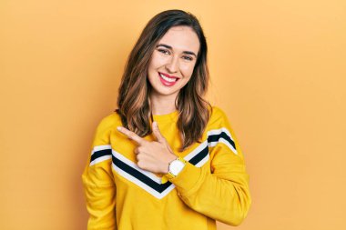 Gündelik kıyafetler giyen, neşeli, yüzünde bir gülümseme olan genç İspanyol kız mutlu ve doğal bir ifadeyle elini ve parmağını kaldırdı. 