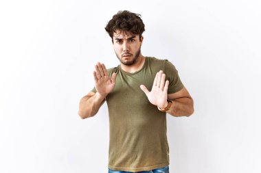 İspanyol bir adam, izole edilmiş beyaz arka planda duruyor. Avuçlarını hareket ettiriyor. Korkmuş ve iğrenç bir ifadeyle reddediyor. Dur ve yasakla. 