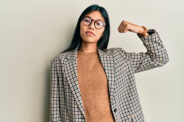 İş stili ve gözlük takan genç Çinli kadın kol kası gösteren güçlü, kendinden emin ve gururlu biri. 