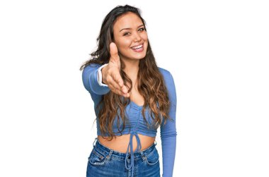 Gündelik kıyafetler giyen genç İspanyol kız dostça bir selamlama ve hoş geldin hediyesi olarak el sıkışmayı sunuyor. başarılı iş. 