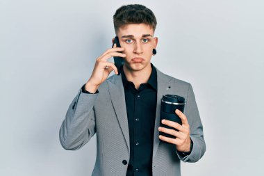 Kulakları büyüyen, akıllı telefon kullanan, bir fincan kahve içen, bunalımlı, sıkıntılı, sinirli ve korkmuş bir beyaz çocuk. hüzünlü ifade. 