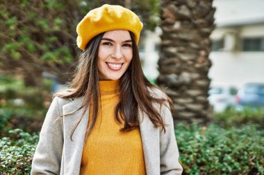 Genç İspanyol kız gülümseyerek şehirde mutlu mesut dikiliyor..