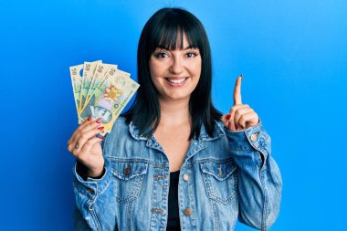 50 Romen Ley banknotunu elinde tutan genç İspanyol kadın bir fikir veya soruyla gülümsüyor ve mutlu bir yüzle işaret ediyor. 