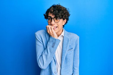 İş ceketi giyen, gözlüklü, stresli ve gergin görünen ağzı tırnak yiyen İspanyol bir genç. anksiyete. 