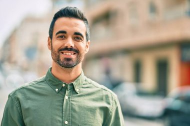 Genç İspanyol adam gülümseyerek şehirde mutlu mesut dikiliyor..