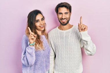 Gündelik giysiler giyen genç İspanyol çift başarılı bir fikri işaret ediyor. Heyecanlı ve mutlu. Bir numara.. 