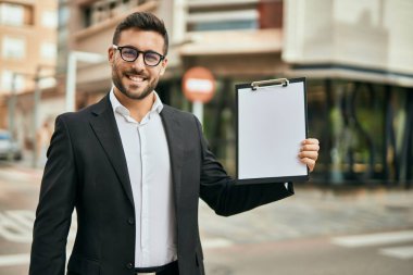 Genç İspanyol işadamı gülümsüyor. Şehirde elinde bir pano var..