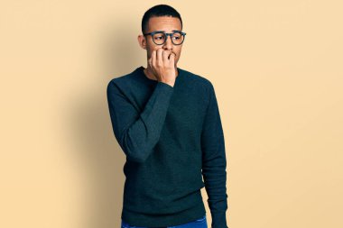 Gündelik kıyafetler ve gözlük takan genç Afro-Amerikan adam elleri ağız yiyen tırnaklarla stresli ve gergin görünüyor. anksiyete. 