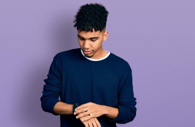 Rahat ve kendinden emin genç Afro-Amerikan bir adam bilek saatine bakıyor. 