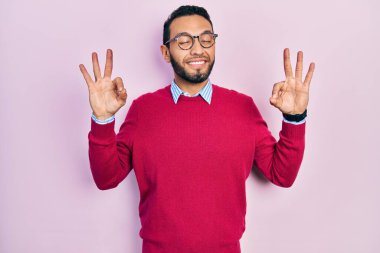 Sakallı, iş gömleği ve gözlük takan, gözleri kapalı gülümseyen, parmaklarıyla meditasyon yapan İspanyol bir adam. yoga konsepti. 