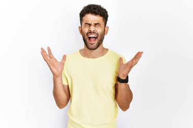 İzole edilmiş arka planda duran Arap genç adam başarının çılgınlığını kollarını kaldırmış ve gözlerini kapatmış heyecanla haykırarak kutluyor. Kazanan konsept 