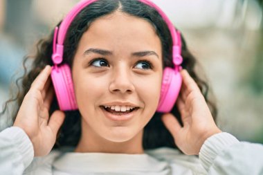 Şehirde kulaklık takıp gülümseyen İspanyol çocuk..