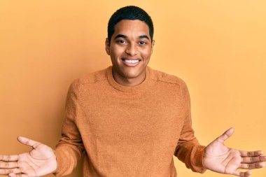 Sıradan bir kazak giyen genç, yakışıklı bir İspanyol. Kolları ve elleri havada, kafası karışık bir ifade takınıyor. şüphe kavramı. 