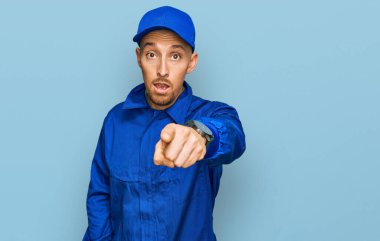 Sakallı, inşaatçı tulumu giymiş kel bir adam kameraya kızgın ve sinirli olduğunu gösteriyor. 