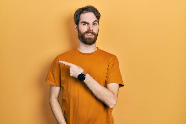 Sakallı, sarı tişörtlü beyaz bir adam endişeli, endişeli ve şaşırmış bir ifade takınıyor. 