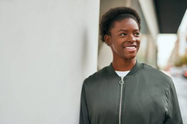 Genç Afrikalı Amerikalı kız gülümseyerek şehirde mutlu mesut duruyor..