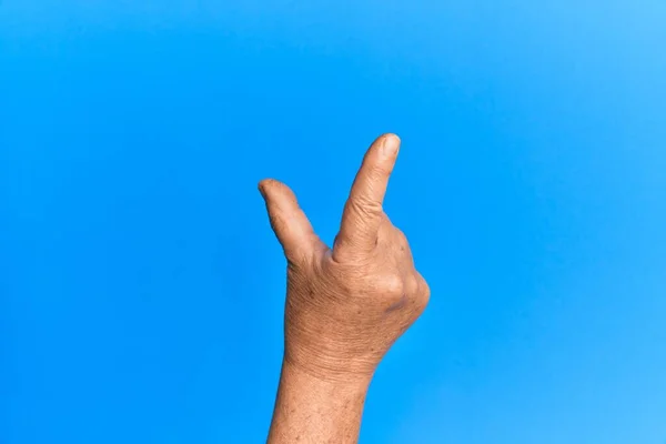 Hand Van Senior Spaanse Man Blauw Geïsoleerde Achtergrond Plukken Nemen — Stockfoto